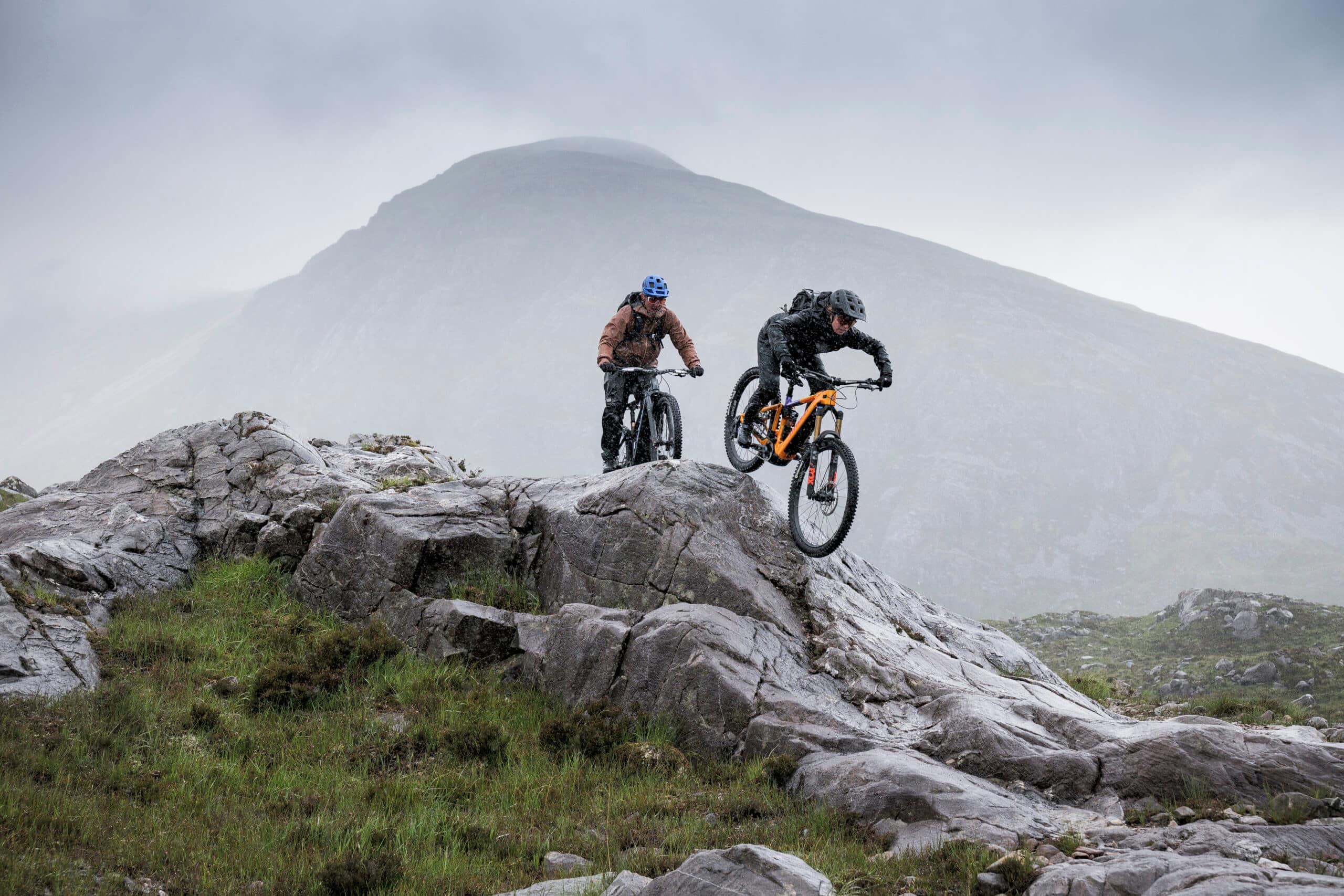 Two mountain bikers navigating rocky terrain in a dramatic landscape, showcasing adventure and skill by Ghost E-Riot Photo and Video Production. - Alexi Hall
